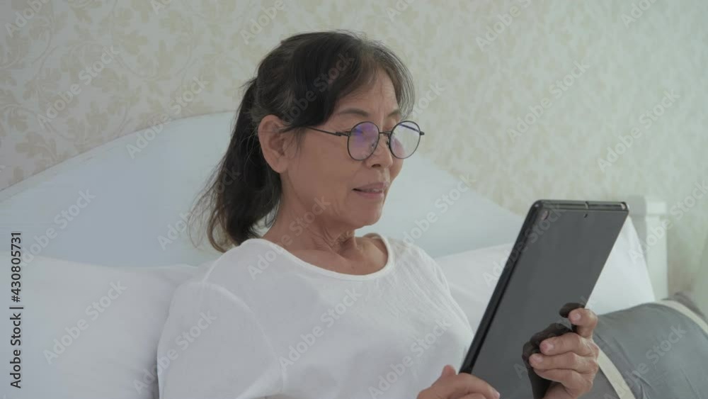 Holiday concept of 4k Resolution. Asian old woman using a tablet in the bedroom. Holiday concept of 4k Resolution. Asian old woman using a tablet in the bedroom.
