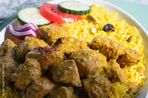 Garnished chicken Madras with Pulao rice in a white bowl