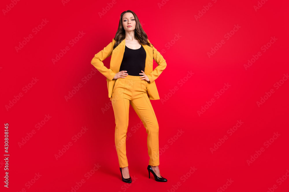 Photo of charming confident young lady dressed yellow blazer arms waist isolated red color background Photo of charming confident young lady dressed yellow blazer arms waist isolated red color background