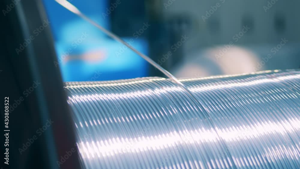 Close up view of silver electrical wire unwinding from a spool Close up view of silver electrical wire unwinding from a spool