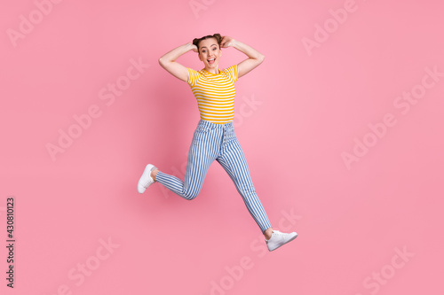 Full length photo of cheerful pretty girl jumping arms touch hair have good mood isolated on pink color background