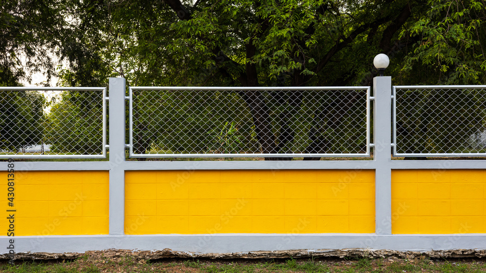 Yellow concrete wall fence with forest garden. Yellow concrete wall fence with forest garden.