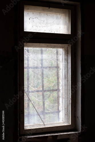 Dirty old window with bars in abandoned house in ghost town Pripyat, Chernobyl Exclusion Zone, Ukraine. Vertical photo