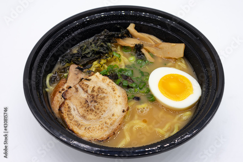 Black Bowl of Shoyu Ramen filled with Pork and an Egg on a White Background