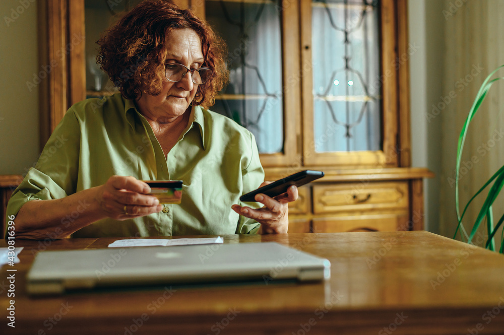 Senior woman using a smartphone and a credit card at home Senior woman using a smartphone and a credit card at home