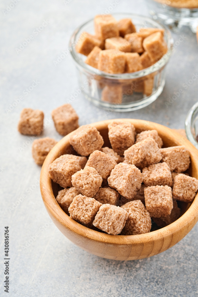 Cane sugar cube in bamboo bowl on gray table concrete background. Top view. Cane sugar cube in bamboo bowl on gray table concrete background. Top view.