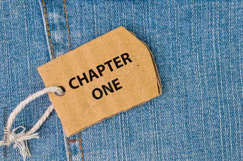 Label tag written with CHAPTER ONE on blue jeans.
