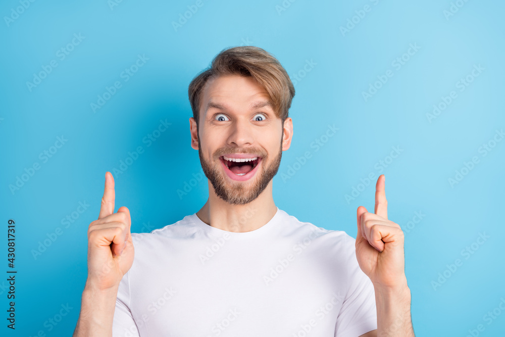 Photo of impressed positive guy open mouth indicate finger up empty space isolated on blue color background Photo of impressed positive guy open mouth indicate finger up empty space isolated on blue color background