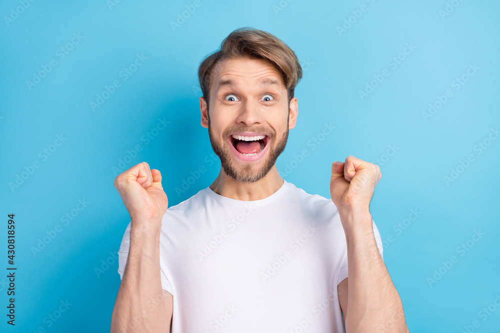 Photo portrait of amazed guy wearing casual t-shirt gesturing like winner isolated on bright blue color background Photo portrait of amazed guy wearing casual t-shirt gesturing like winner isolated on bright blue color background