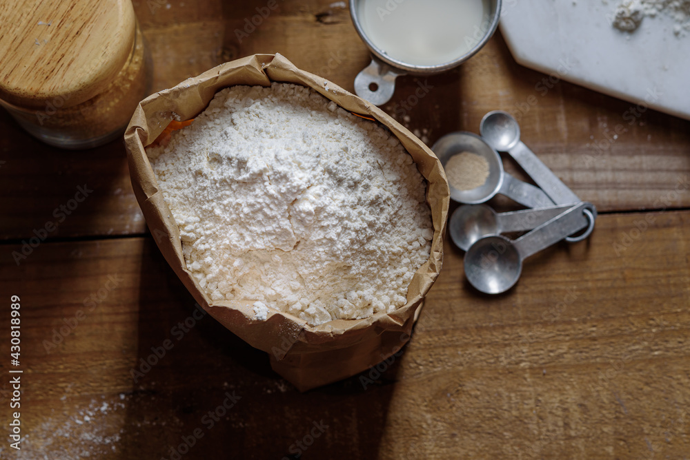 The powder of flour is in a paper bag and placed on a wooden table Prepare for cooking. The powder of flour is in a paper bag and placed on a wooden table Prepare for cooking.