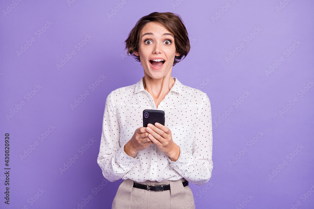 Portrait of nice brunette short hairdo impressed lady hold telephone wear white shirt isolated on lilac color background Portrait of nice brunette short hairdo impressed lady hold telephone wear white shirt isolated on lilac color background