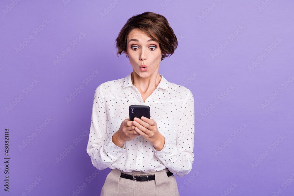 Portrait of nice brunette short hairdo impressed lady hold telephone wear white shirt isolated on lilac color background Portrait of nice brunette short hairdo impressed lady hold telephone wear white shirt isolated on lilac color background