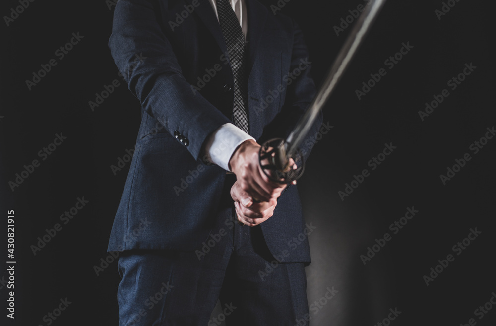 スーツを着て日本刀を構える男性
