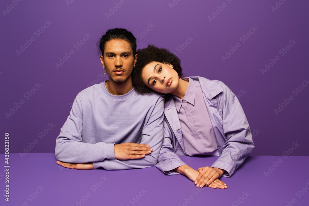 Obraz premium young african american woman leaning on man isolated on purple