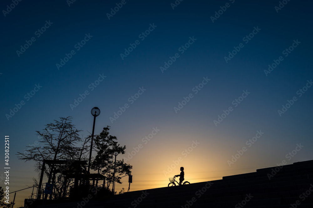 夕暮れの高台のシルエット、自転車の女の子、宝塚市北公園、4月19日、日本