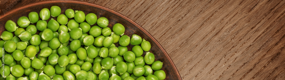 Fresh green peas in a brown plate with copy space banner
