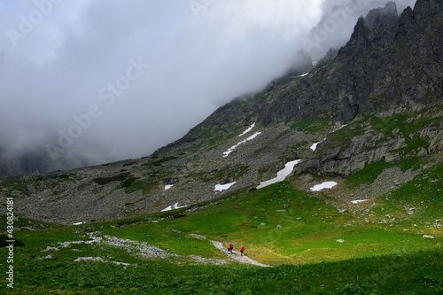 Landscape of the High Tatra mountains. Hikers on a track above Lake Velicke pleso and waterfall Velicky vodopad. Slovakia. photo
