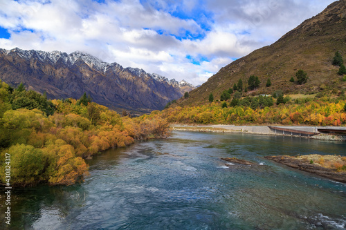 Autumn landscape near Queenstown, New Zealand. The Kawarau River, surrounded by willow trees, and the Remarkables mountain range