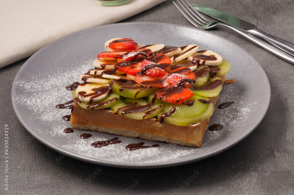waffle with kiwi banana and strawberries drizzled with chocolate syrup waffle with kiwi banana and strawberries drizzled with chocolate syrup