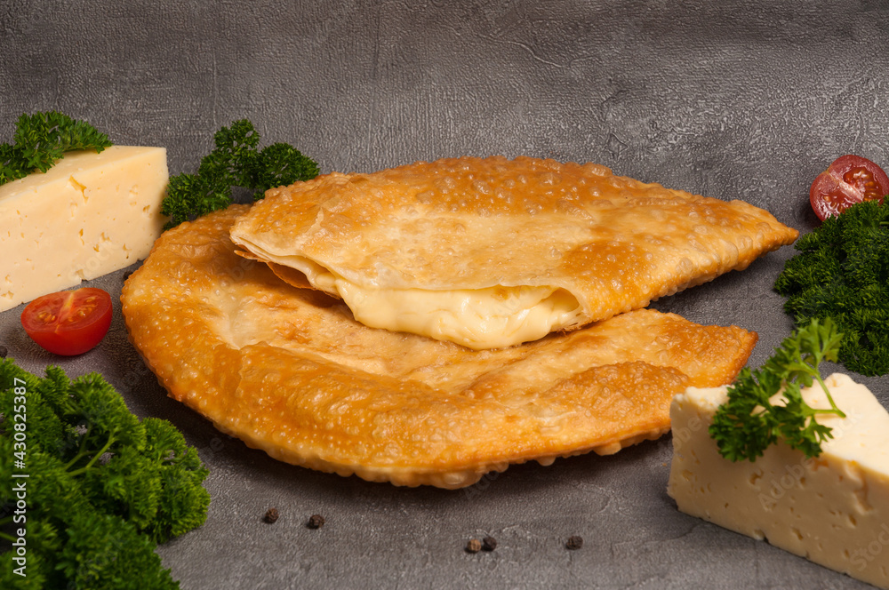 hot appetizer: cheburek with cheese on a gray background hot appetizer: cheburek with cheese on a gray background
