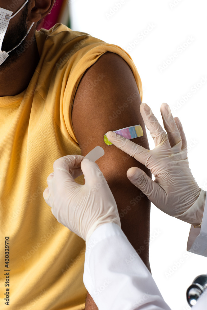 Cropped view of doctor in latex gloves applying adhesive plaster on arm of african american patient isolated on white