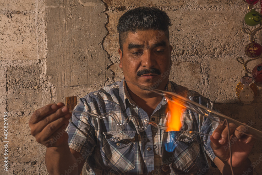Craftsman blowing glass to create Christmas balls in his with