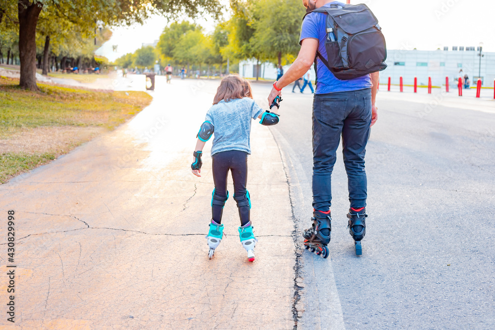 Little girl learning to roller skating with her father. girl and father
