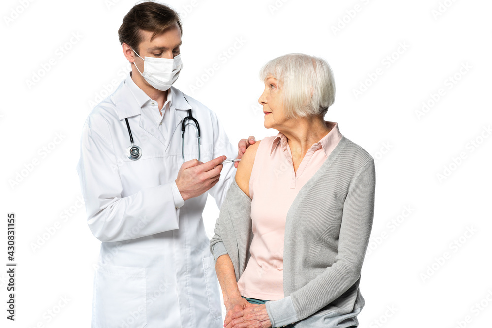 Senior patient looking at doctor in medical mask during vaccination isolated on white Senior patient looking at doctor in medical mask during vaccination isolated on white