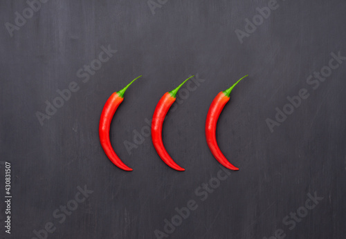 Selection of red Chilli peppers over grey background. Spicy food rating concept. Flat lay.