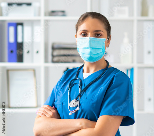 Professional medical doctor working in hospital office, Portrait of young and attractive female physician in protective mask.