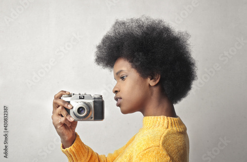 young black woman holds a vintage camera © olly