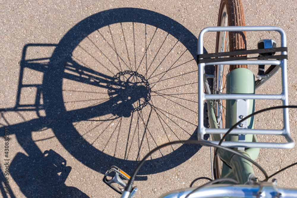 Sustainability by showing a top view of a bicycle tire and rim shadow on a rural road in sunlight.