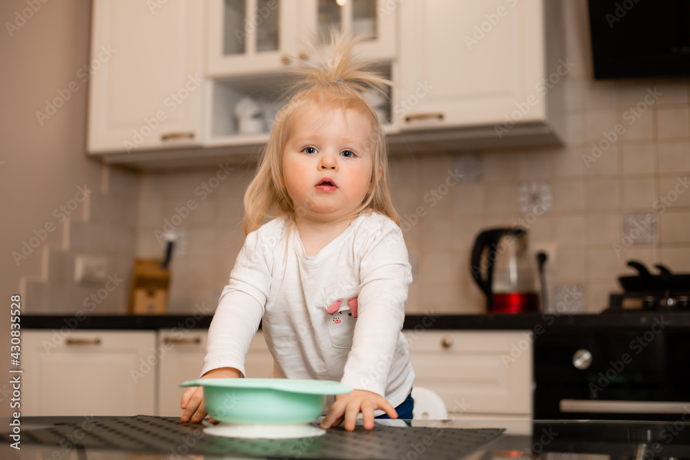 Cute little blonde girl eats in the kitchen of the house Cute little blonde girl eats in the kitchen of the house