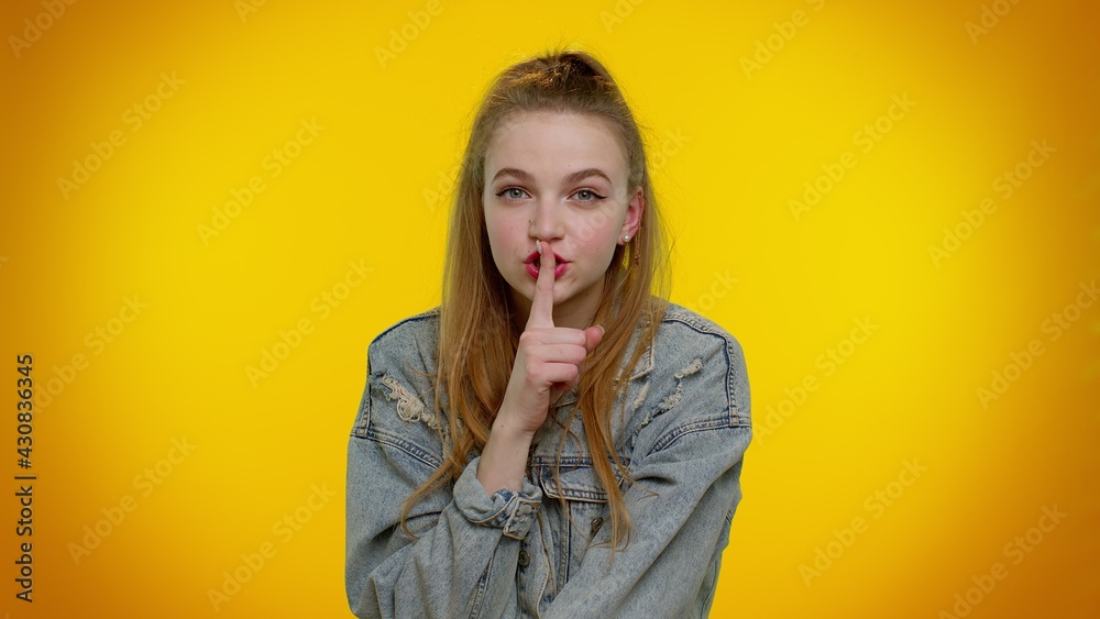 Shh be quiet please. Portrait of teenager student girl 20s years old presses index finger to lips makes silence gesture sign do not tells secret. Young adult woman posing on yellow studio background Shh be quiet please. Portrait of teenager student girl 20s years old presses index finger to lips makes silence gesture sign do not tells secret. Young adult woman posing on yellow studio background