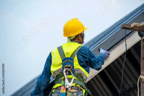 Bild auf Leinwand Professional and qualified roofer in protective uniform wear use electric drill to install the metal sheet on the new roof of new modern building construction