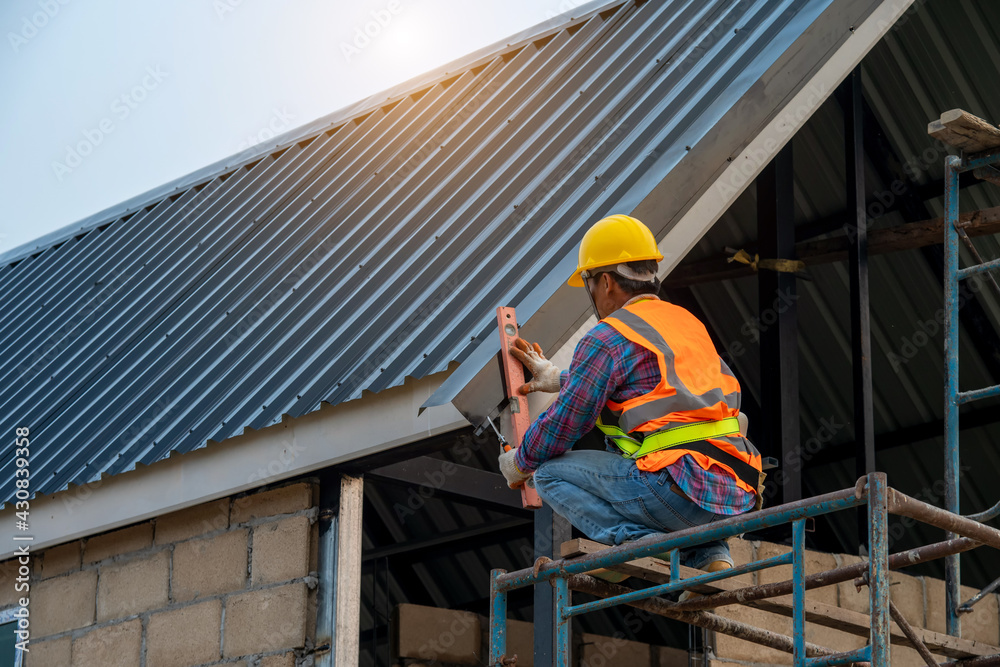 Two roofers inspecting and install new roof,Roofer using air or pneumatic nail gun and installing Metal Sheet on top roof. Two roofers inspecting and install new roof,Roofer using air or pneumatic nail gun and installing Metal Sheet on top roof.