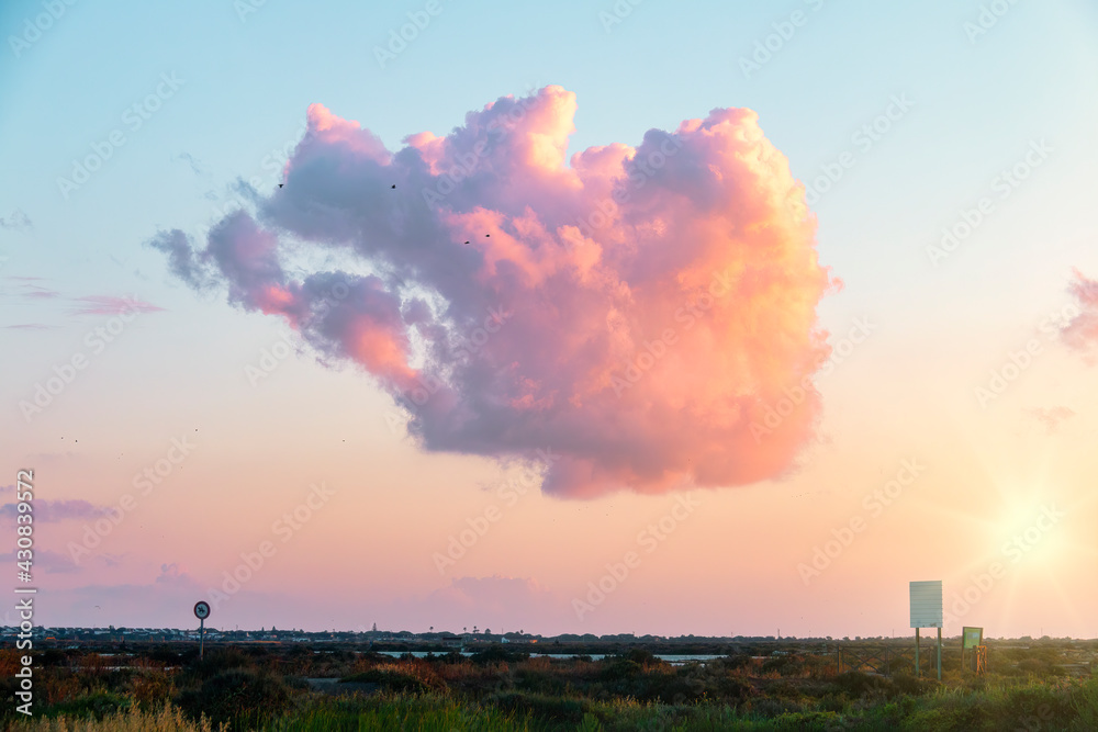 A beautiful cloud of reddish tones in a sunset in the marshes of Chiclana de la Frontera, Cadiz, Spain