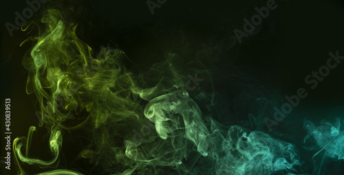 Bluish-green swirl of smoke on black background. Abstract ethereal backdrop