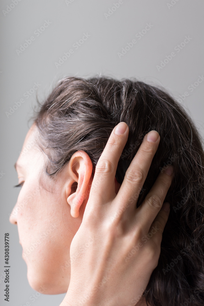 40 year old woman pulling hair back; natural gray hair growing in