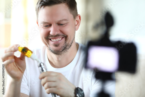 Smiling man fills marijuana vaporizer for smoking and takes pictures