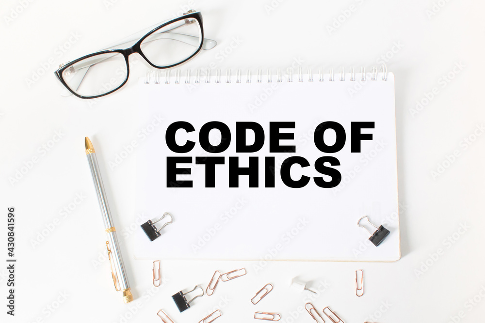 Notepad with text CODE OF ETHICS on the office desk with stationery. A blank notepad for entering a copy or text. business Notepad with text CODE OF ETHICS on the office desk with stationery. A blank notepad for entering a copy or text. business