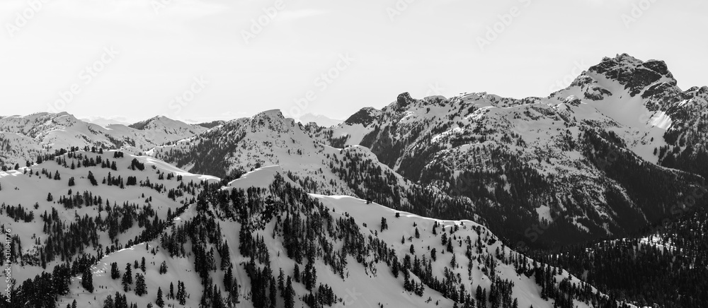Aerial View from Airplane of Snow Covered Canadian Mountain Landscape in Winter. Bright Sunny Sky. North of Vancouver, British Columbia, Canada. Black and White Art Render