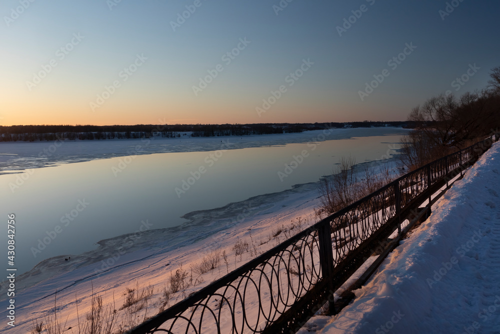 Sunset on the Volga in March with an embankment element
