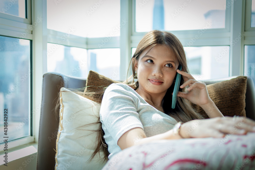 Beautiful Asian girl at the sofa using smartphone Beautiful Asian girl at the sofa using smartphone