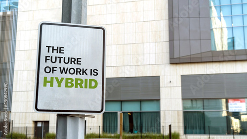 The Future of Work is Hybrid sign in a downtown city setting 