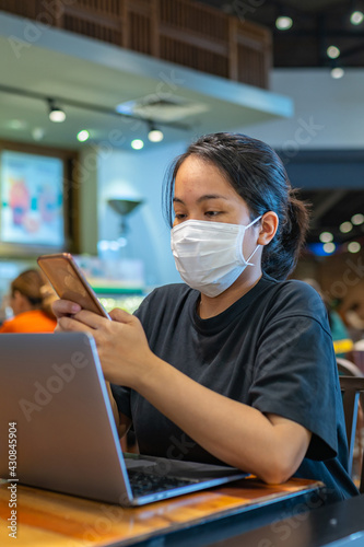 Portrait of Asian woman wearing medical mask and using smartphone