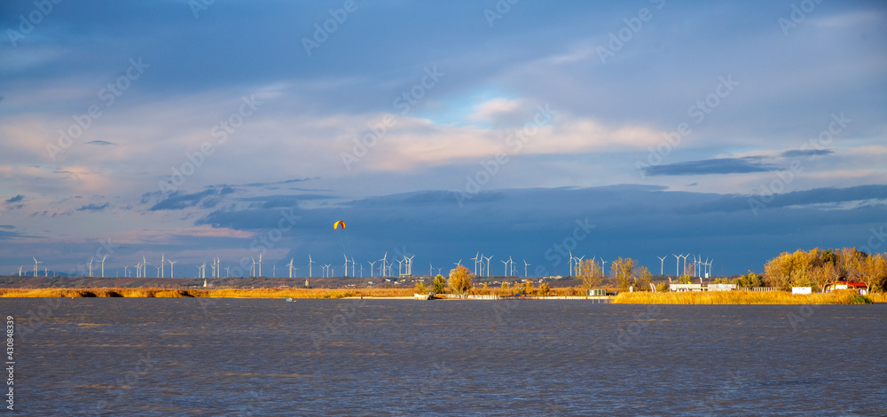 Herbstabend am Neusiedler See - Kitesurfer  in der Abendsonne vor Windradpark am Ufer, Niederösterreich