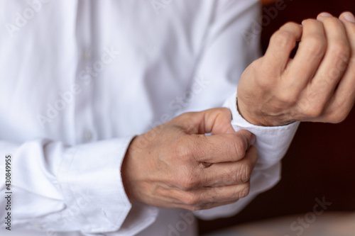 Hands of a man buttoning the sleeve of a shirt