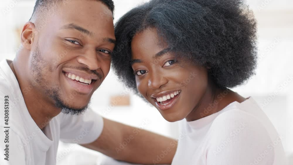Loving young african couple bonding laughing smiling touching foreheads together looking at camera, romantic millennial afro man and happy black woman getting closer enjoying affection moment at home Loving young african couple bonding laughing smiling touching foreheads together looking at camera, romantic millennial afro man and happy black woman getting closer enjoying affection moment at home