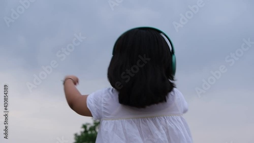 Little girl listening music. Shoot from back side.